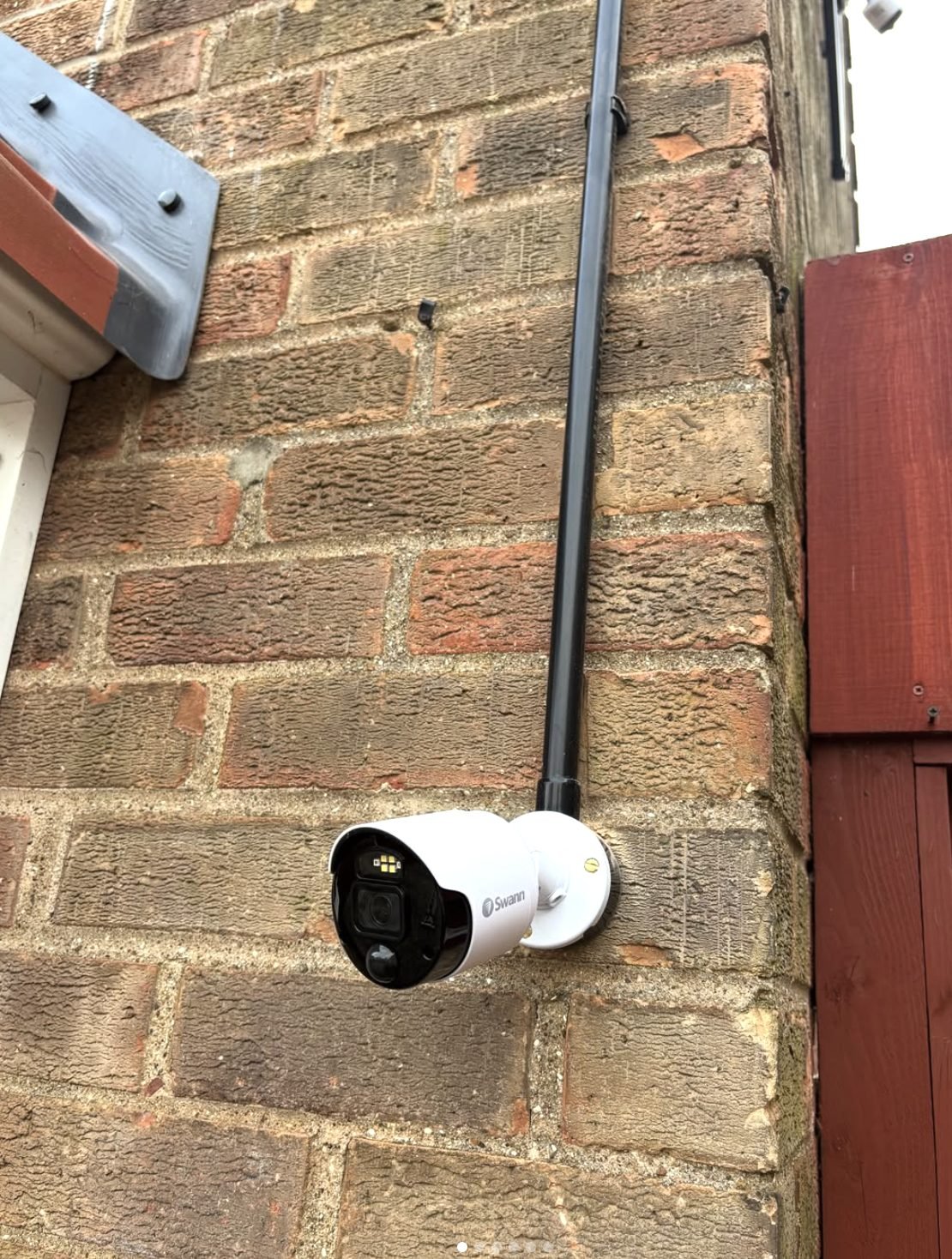 Swann CCTV camera installed neatly on a brick wall beside a downpipe