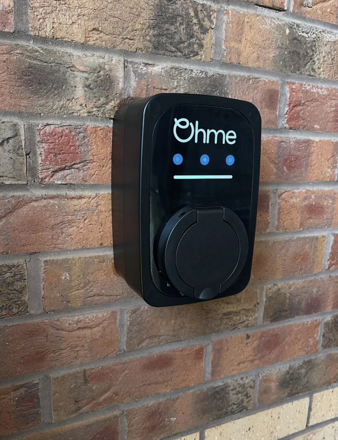 Ohme untethered EV charger installed on a brick house wall